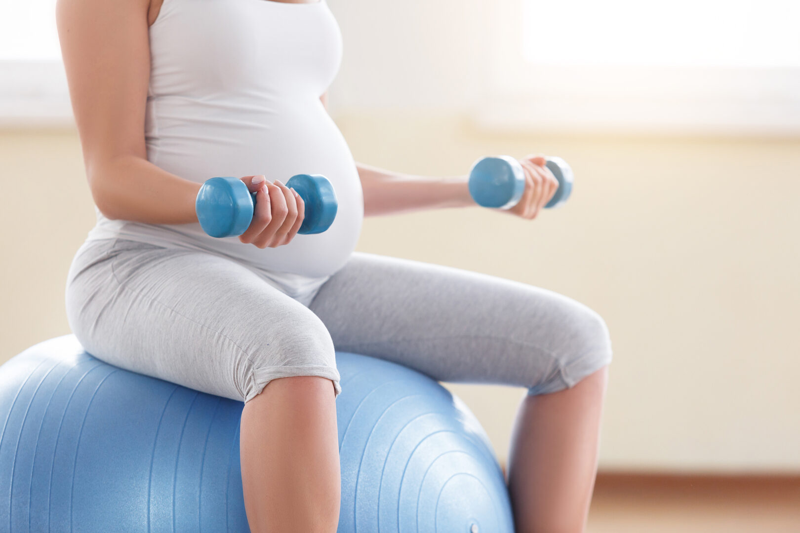 portrait of a beautiful young pregnant woman executing exercises with fitball